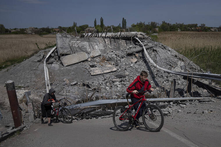 ASSOCIATED PRESS
                                Teenagers on bicycles passed a bridge destroyed by shelling near Orihiv, Ukraine, Thursday.