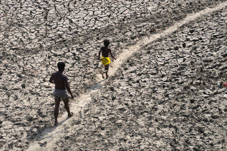 ASSOCIATED PRESS / MAY 2
                                A man and a boy walk across the almost dried-up bed of river Yamuna following hot weather in New Delhi, India. According to a report released by the World Meteorological Organization today, the world is creeping closer to the warming threshold international agreements are trying to prevent, with nearly a 50-50 chance that Earth will temporarily hit that temperature mark within the next five years.