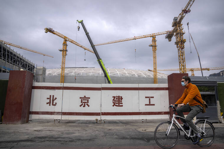 ASSOCIATED PRESS
                                A man wearing a face mask rides a bicycle past a construction site in Beijing.