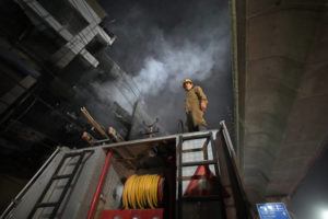 MANISH SWARUP / AP
                                A fire official stands on a fire brigade truck to help his colleagues douse a fire in a four storied building, in New Delhi, India.