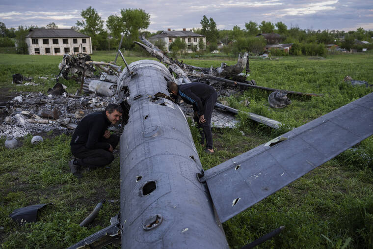 ASSOCIATED PRESS
                                Oleksiy Polyakov, right, and Roman Voitko check the remains of a destroyed Russian helicopter lie in a field in the village of Malaya Rohan, Kharkiv region, Ukraine, today.