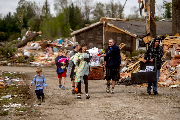 JAKE MAY/MLIVE.COM/THE FLINT JOURNAL VIA AP
                                Resident Stephanie Kerwin, center, holds her baby Octavius in one arm and dog Pixie in the other as she and her family carry what they could salvage from her home in Nottingham Forest Mobile Home Park in Gaylord, Mich., following a tornado the day before. “This morning is when it first hit me…I could have lost people that I really love. I am so grateful,” Kerwin said.