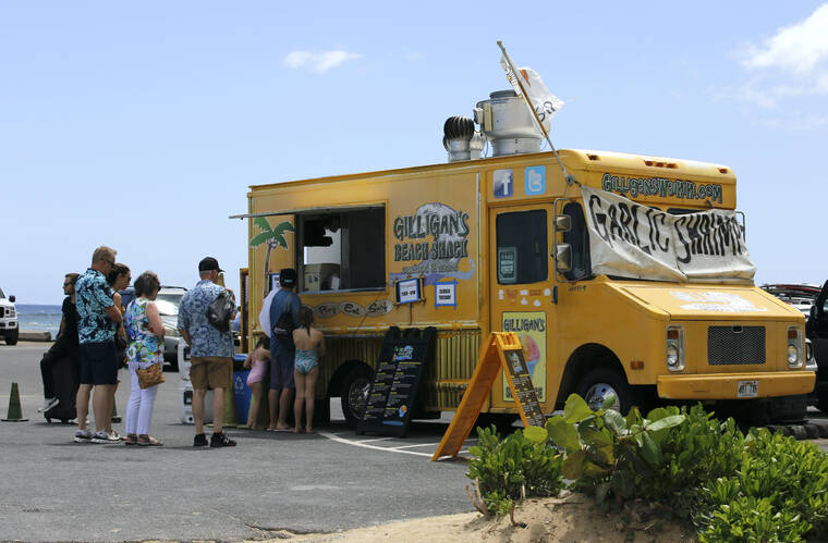 ASSOCIATED PRESS
                                People line up at a food truck parked near Waikiki Beach in Honolulu, Monday. A COVID surge is starting to cause disruptions as schools wrap up for the year and Americans prepare for summer vacations.