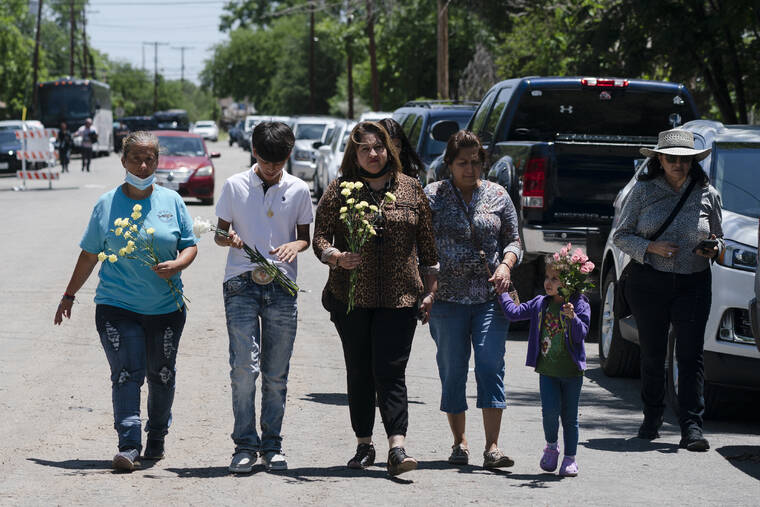 ASSOCIATED PRESS / MAY 25
                                People walk with flowers to honor the victims in Tuesday’s shooting at Robb Elementary School in Uvalde, Texas. Desperation turned to heart-wrenching sorrow for families of grade-schoolers killed after an 18-year-old gunman barricaded himself in their Texas classroom and began shooting, killing at least 19 fourth-graders and their two teachers.