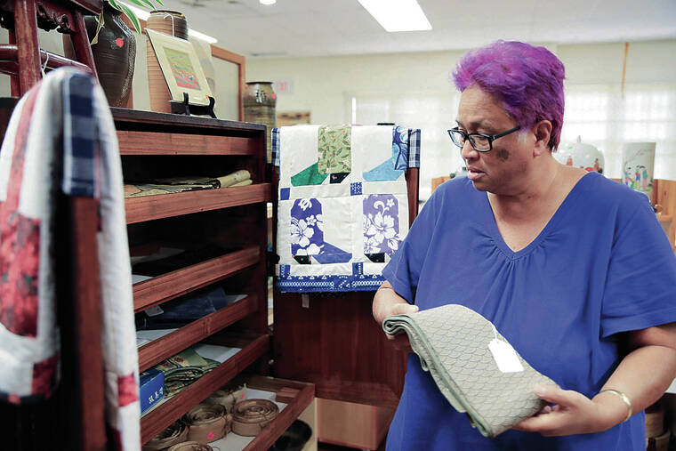 JAMM AQUINO / JAQUINO@STARADVERTISER.COM
                                Evelyn Ahlo, executive director of the Hawaii Plantation Village, holds an obi sash for a kimono, one of the many items in the Country Store donated by the community.