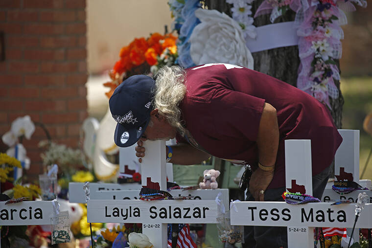 DARIO LOPEZ-MILLS / AP
                                A man kisses the cross of Layla Salazar at a memorial outside Robb Elementary School to honor the victims killed in this week’s school shooting in Uvalde, Texas, Saturday.