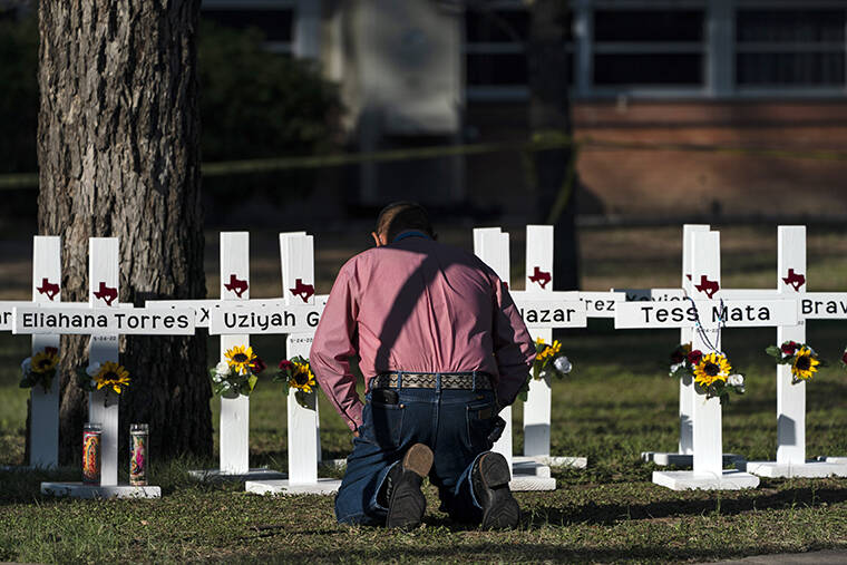 JAE C. HONG / AP
                                Pastor Daniel Myers kneels in front of crosses bearing the names of Tuesday’s shooting victims while praying for them at Robb Elementary School in Uvalde, Texas, Thursday.