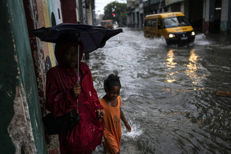 RAMON ESPINOSA / AP
                                Children walk through their neighborhood street flooded by heavy rains, in Havana, Cuba, Friday.