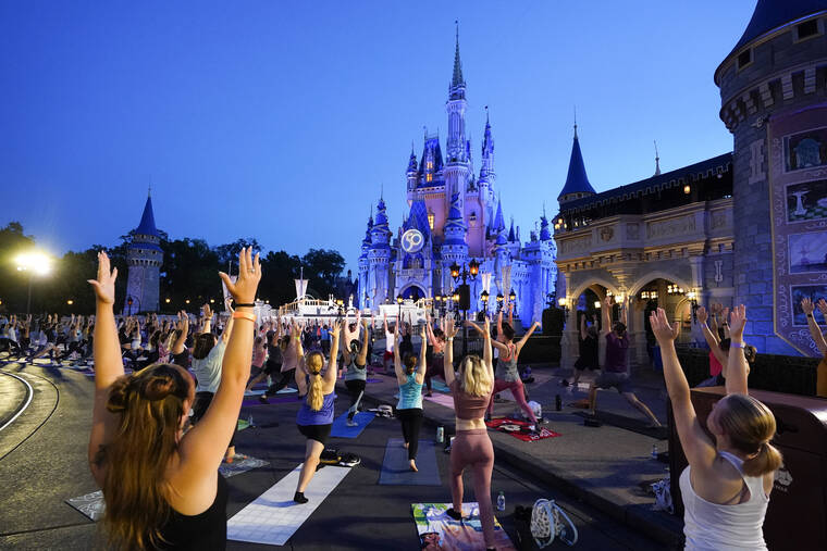 ASSOCIATED PRESS Nearly 2,000 Cast Members practice sunrise yoga celebrating International Yoga Day in front of Cinderella Castle at the Magic Kingdom Park at Walt Disney World today, in Lake Buena Vista, Fla.