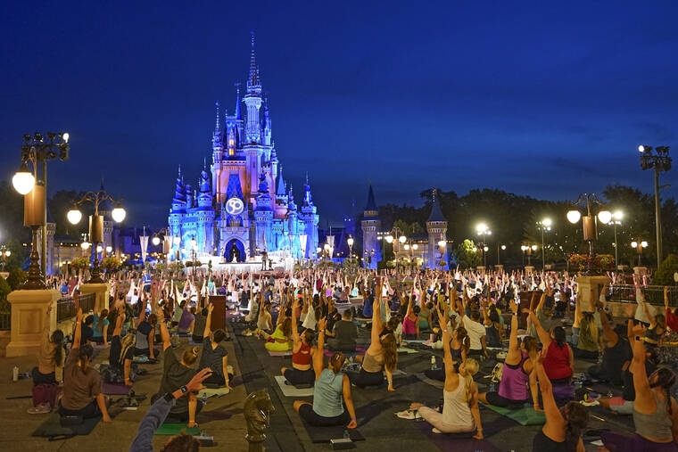 ASSOCIATED PRESS Nearly 2,000 cast members practice sunrise yoga celebrating International Yoga Day in front of Cinderella Castle at the Magic Kingdom Park at Walt Disney World today, in Lake Buena Vista, Fla.