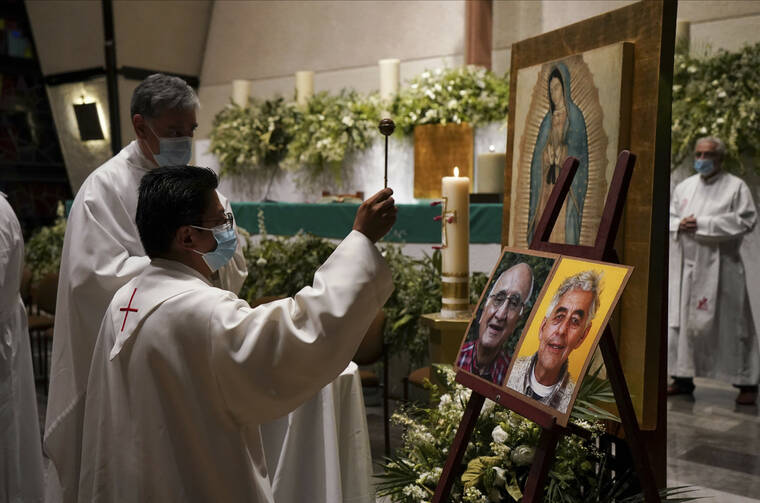 ASSOCIATED PRESS
                                A priest blesses the photos of Jesuit priests Javier Campos Morales, left, and Joaquin Cesar Mora Salazar during a Mass to mourn them at a church in Mexico City today.