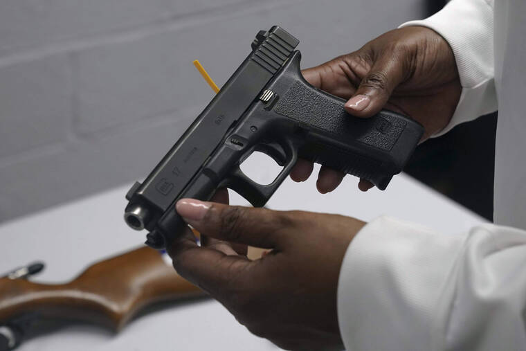 ASSOCIATED PRESS
                                A handgun from a collection of illegal guns is reviewed during a gun buyback event in Brooklyn, N.Y., in May 2021. The Supreme Court, today, struck down a restrictive New York gun law in a major ruling for gun rights.