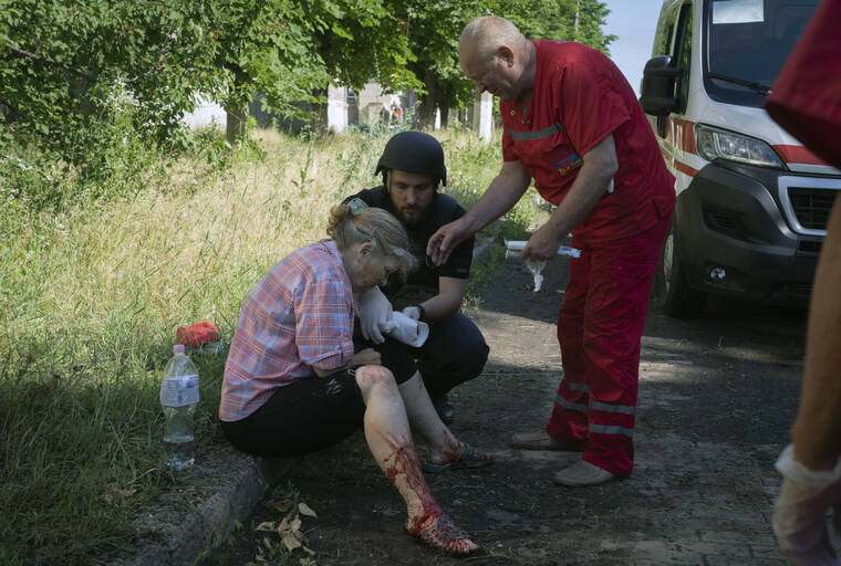 ASSOCIATED PRESS
                                A police officer and paramedic give first aid to a woman wounded by the Russian shelling in city center in Slavyansk, Donetsk region, Ukraine, today.