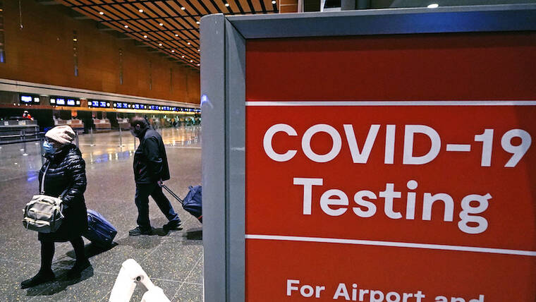 ASSOCIATED PRESS / 2021
                                Travelers pass a sign near a COVID-19 testing site in Terminal E at Logan Airport in Boston.