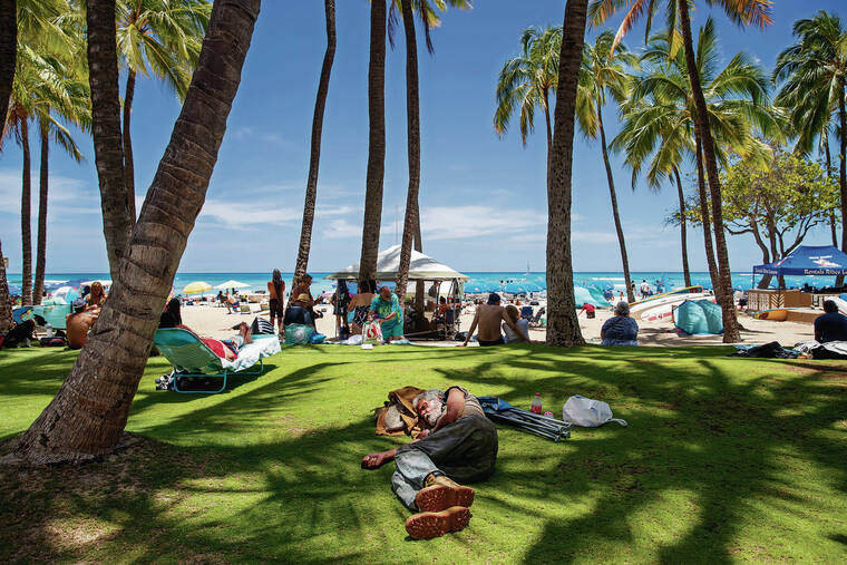 CINDY ELLEN RUSSELL / CRUSSELL@STARADVERTIESR.COM
                                A man slept Sunday among people visiting the beach in Waikiki.