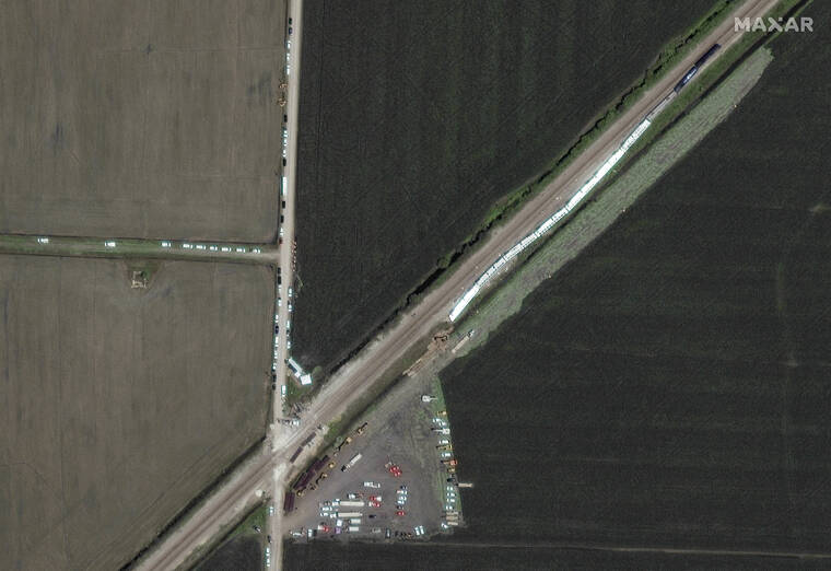 SATELLITE IMAGE ©2022 MAXAR TECHNOLOGIES VIA AP / JUNE 28
                                Sn Amtrak train, at right, that derailed a day earlier along the rail line and dozens of cars, heavy lift equipment and rescue vehicles positioned nearby near Mendon, Mo.