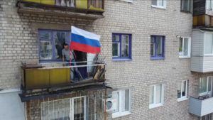 RUSSIAN DEFENSE MINISTRY PRESS SERVICE VIA ASSOCIATED PRESS
                                In this handout photo taken from video released by the Russian Defense Ministry Press Service today, a man sets a Russian national flag on a balcony of a residential building in Lysychansk, which is now territory under the Government of the Luhansk People’s Republic control, eastern Ukraine.