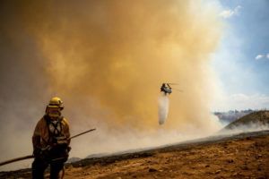 NOAH BERGER / AP
                                A helicopter drops water while battling the Electra Fire in the Pine Acres community of Amador County, Calif., on Tuesday.