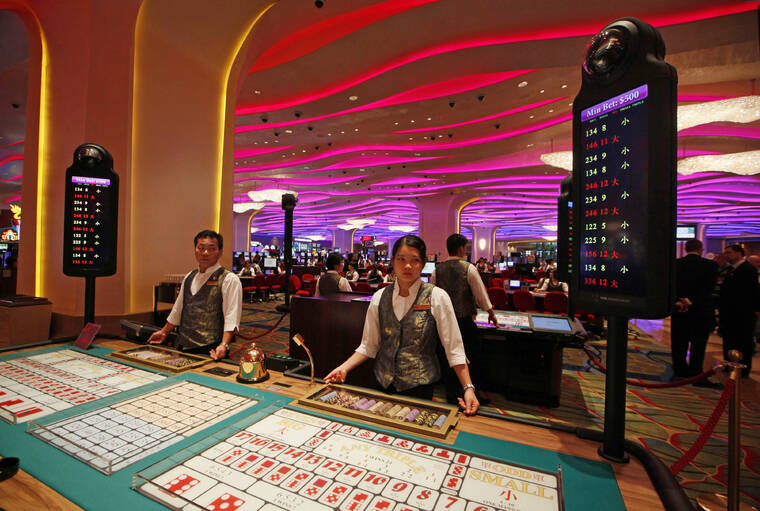 ASSOCIATED PRESS / 2012 Croupiers stand at a Sic Bo gaming table inside a casino at the Sands Cotai Central in Macao. The Asian gambling center of Macao will close all its casinos for a week starting Monday, July 11, and largely restrict people to their homes as it tries to stop a COVID-19 outbreak that has infected more than 1,400 people in the past three weeks.