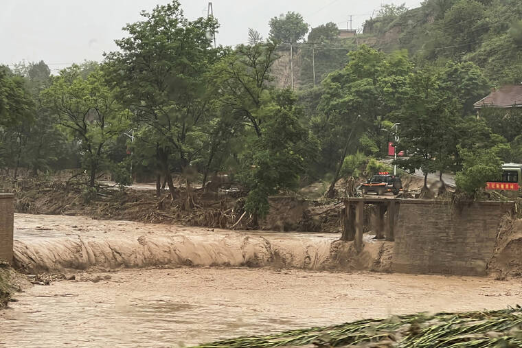 CHINATOPIX VIA AP / JULY 16
                                A vehicle is seen near a part of a bridge that was washed away by flood waters along a river in Qingyang in northwest China’s Gansu province. Flash floods in southwest and northwest China have left at least a dozen dead and put thousands of others in harm’s way, state media reported Sunday.