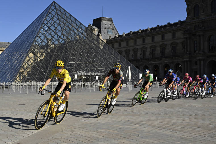 BERTRAND GUAY/POOL VIA AP The pack with Denmarks Jonas Vingegaard, wearing the overall leaders yellow jersey, passes the Louvre Museum during the twenty-first stage of the Tour de France cycling race over 116 kilometers (72 miles) with start in Paris la Defense Arena and finishing on the Champs Elysees in Paris, France.