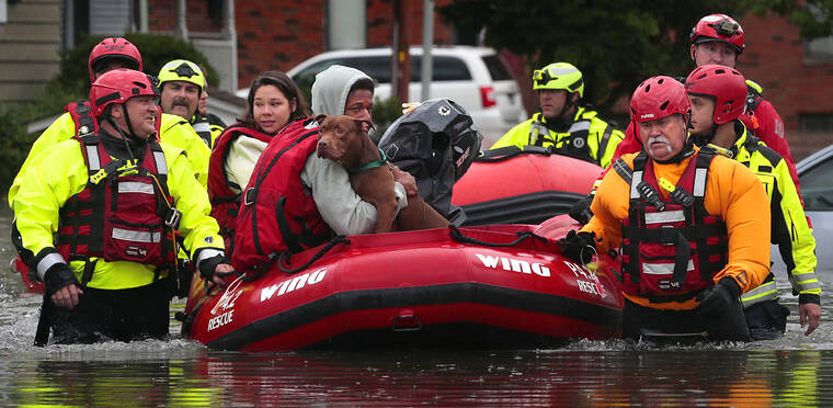 ROBERT COHEN/ST. LOUIS POST-DISPATCH VIA AP
                                Matthew Robinson holds onto his dog Bebe as and Kimberly Tat are rescued from their home by first responders from Central County Fire and Rescue along Main Street in Old Towne St. Peters after flooding from Dardenne Creek inundated the neighborhood during heavy rains.