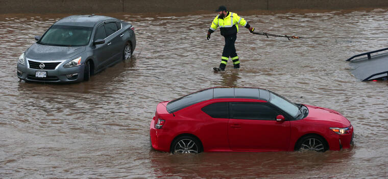 ROBERT COHEN/ST. LOUIS POST-DISPATCH VIA AP
                                A tow truck driver moves to clear a flooded car as another rolls along Interstate 70 at Mid Rivers Mall Drive in St. Peters after heavy rain fell through Monday night and into the morning.