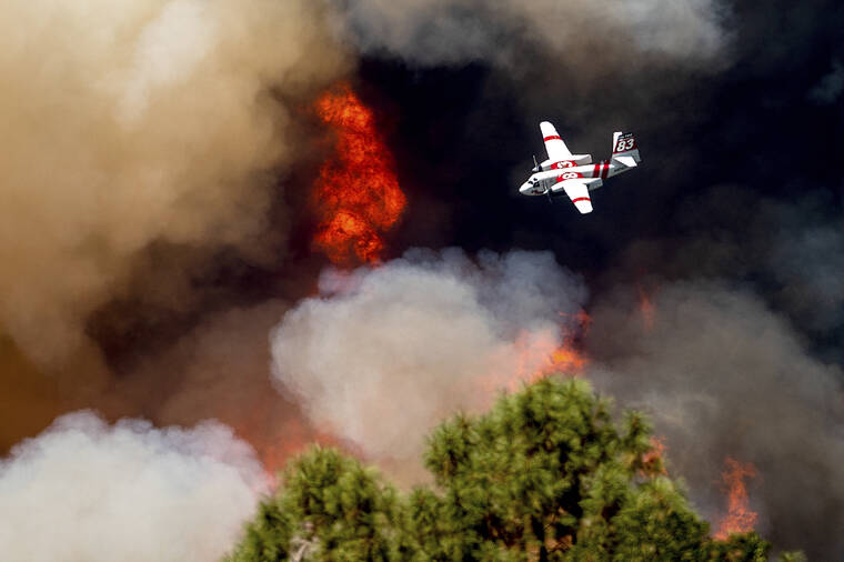 ASSOCIATED PRESS
                                An air tanker flies past flames while battling the Oak Fire in Mariposa County, Calif., Sunday. Wildfires, floods and soaring temperatures have made climate change real to many Americans.