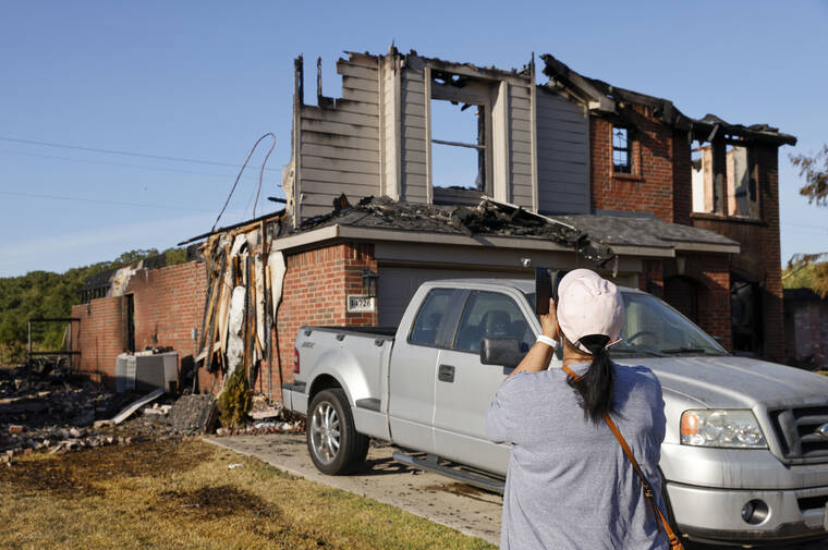 THE DALLAS MORNING NEWS / AP
                                Glenda Jackson, 61, takes a photo of the remains of her home, Tuesday, July 26, in Balch Springs, Texas.