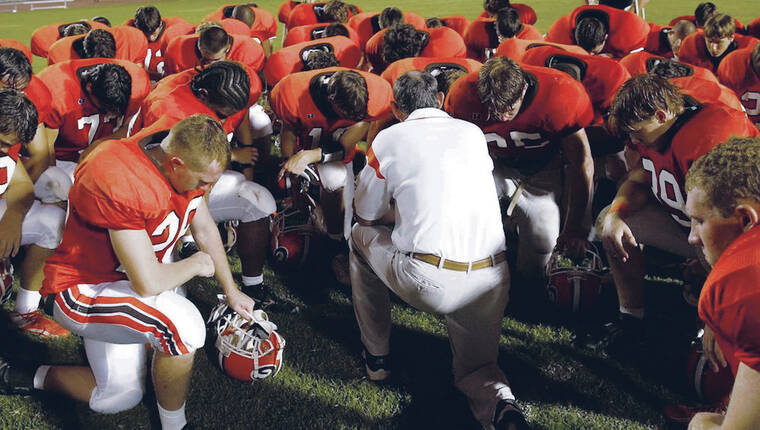 AL.COM / TRIBUNE NEWS SERVICE
                                A football team of a Jefferson County high school in Alabama bows in prayer.