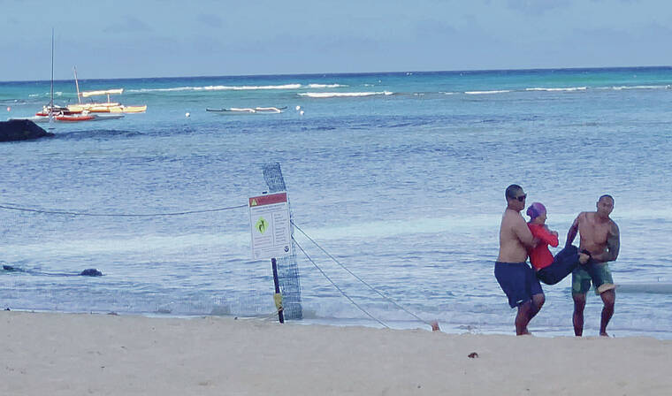 COURTESY MARKUS FAIGLE
                                In this image from video, two men carry a woman after she was injured by Rocky the Hawaiian monk seal Sunday in Waikiki. The state will not fine her for being too close to the monk seal.