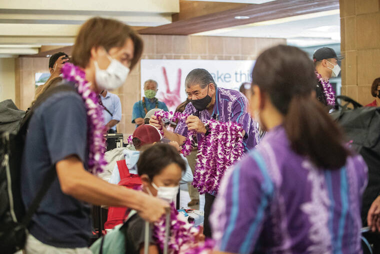 CINDY ELLEN RUSSELL / CRUSSELL@STARADVERTISER.COM 
                                James Higa, an employee of the state Department of Transportation, presented lei Friday to travelers who flew on All Nippon Airways’ “Flying Honu.”