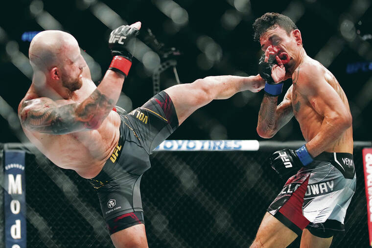 ASSOCIATED PRESS
                                Hawaii’s Max Holloway absorbed a kick to the face from Alexander Volkanovski in a featherweight title bout at UFC 276 in Las Vegas on Saturday.