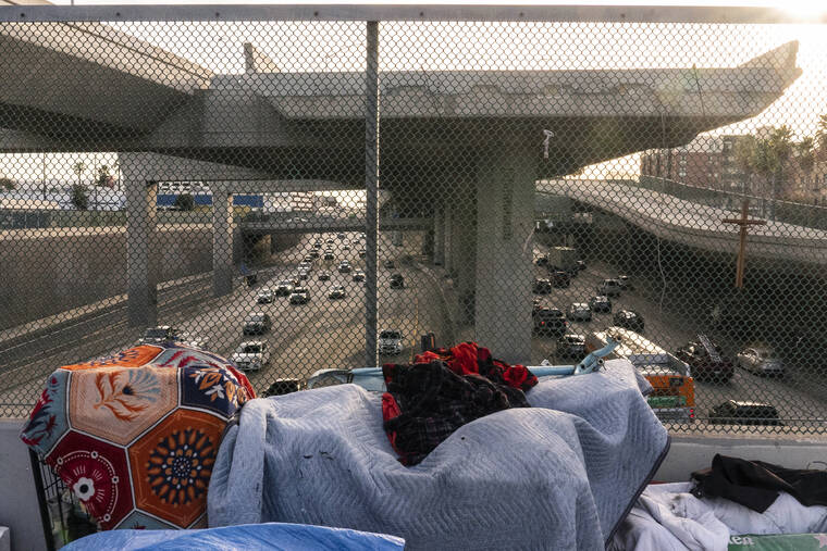 ASSOCIATED PRESS
                                A homeless encampment is seen on a bridge over the CA-110 freeway, Dec. 15, 2021, in Los Angeles. The Los Angeles City Council has voted to ban homeless encampments within 500 feet of schools and daycare centers.