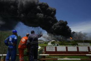 RAMON ESPINOSA / AP
                                Workers of the Cuba Oil Union, known by the Spanish acronym CUPET, watch a huge rising plume of smoke from the Matanzas Supertanker Base, as firefighters work to quell a blaze which began during a thunderstorm the night before, in Matazanas, Cuba, Saturday, Aug. 6.