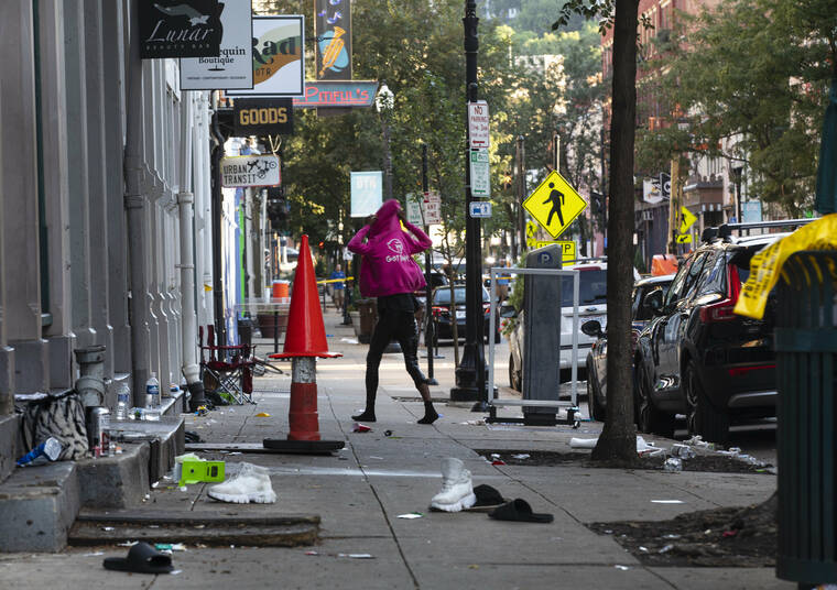 LIZ DUFOUR/THE CINCINNATI ENQUIRER VIA AP
                                A woman looks for her shoes that were left on Main Street in Cincinnati, following an overnight shooting. At least nine people were wounded — none critically — in a shooting outside a Cincinnati bar early Sunday, police said.
