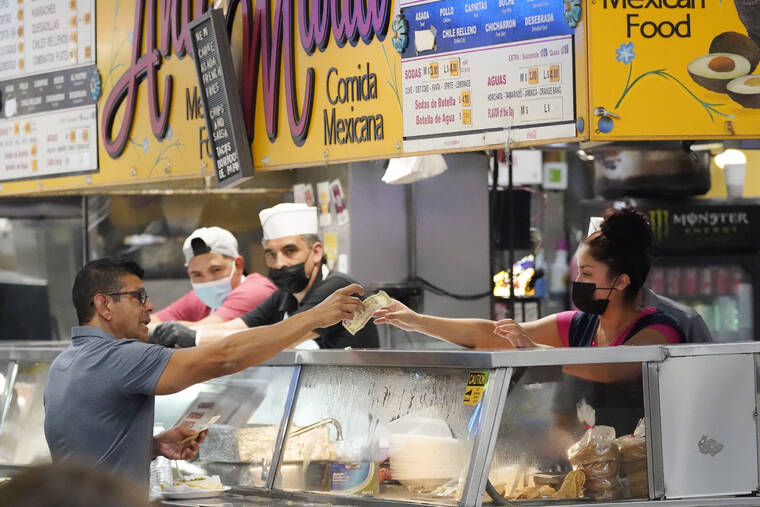 ASSOCIATED PRESS
                                Money is exchanged at a food stand while workers wear face masks inside Grand Central Market, July 13, in Los Angeles. alling prices for gas, airline tickets and clothes helped give Americans a slight break from the pain of high inflation last month, though overall price increases slowed only modestly from a four-decade high that was reached in June.
