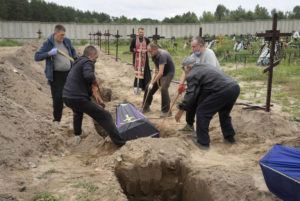 EFREM LUKATSKY / AP
                                Workers put into a grave a coffin with unidentified remains of a civilian murdered by the Russian troops during Russian occupation in Bucha, on the outskirts of Kyiv, Ukraine, Thursday, Aug. 11. Eleven unidentified bodies exhumed from a mass grave were buried in Bucha Thursday. (AP Photo/Efrem Lukatsky)
