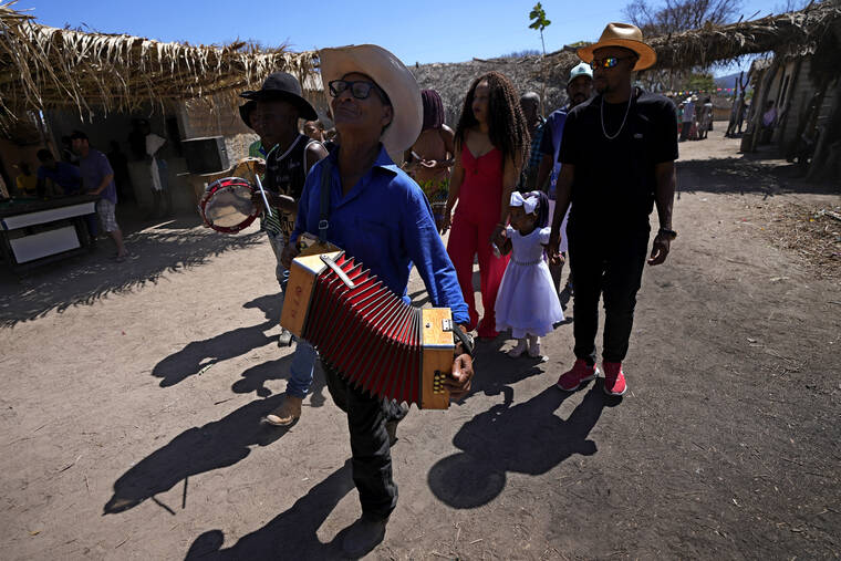 ASSOCIATED PRESS / AUG. 15
                                A family accompanied by musicians walks in procession after a baptism in the chapel of the Kalunga quilombo, during the culmination of the week-long pilgrimage and celebration for the patron saint “Nossa Senhora da Abadia” or Our Lady of Abadia, in the rural area of Cavalcante in Goias state, Brazil, Monday.