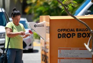 JAMM AQUINO / JAQUINO@STARADVERTISER.COM
                                A woman prepares to drop ballots at Honolulu Hale Friday. Today is the last day to vote in the 2022 Hawaii primary election.