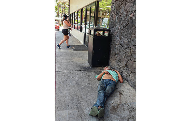 KAT WADE / SPECIAL TO THE STAR-ADVERTISER
                                Above, a homeless man takes a nap in front of the 7-Eleven at the corner of Kalakaua Avenue and Ena Road, where an employee recently severed a man’s hand.