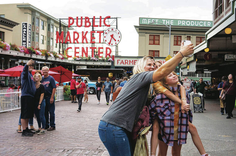 NEW YORK TIMES 
                                Visitors pose for selfies at the iconic Pike Place Market, which is once again packed with people.