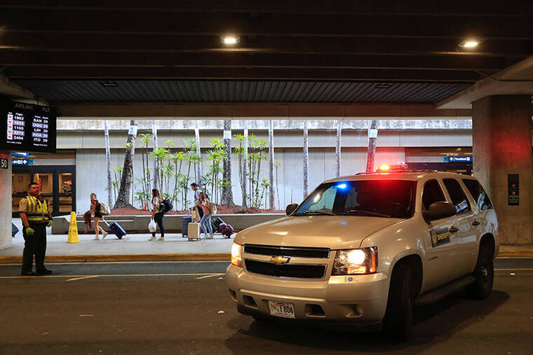 JAMM AQUINO / JAQUINO@STARADVERTISER.COM Travelers walk past a police vehicle near baggage claim 22 at the Daniel K. Inouye International Airport after a suspicious package prompted an evacuation of the area.