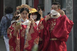 ASSOCIATED PRESS / SEPT. 29
                                A couple dressed in traditional costumes for souvenir photos puts on their masks as they visit the Forbidden City area Beijing, Thursday, Sept. 29.
