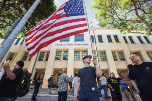 CINDY ELLEN RUSSELL / CRUSSELL@STARADVERTISER.COM
                                Scott Choy held a U.S. flag outside of Honolulu Police Department headquarters, where people gathered Tuesday for a hearing on proposed rules for obtaining licenses to carry guns in public.